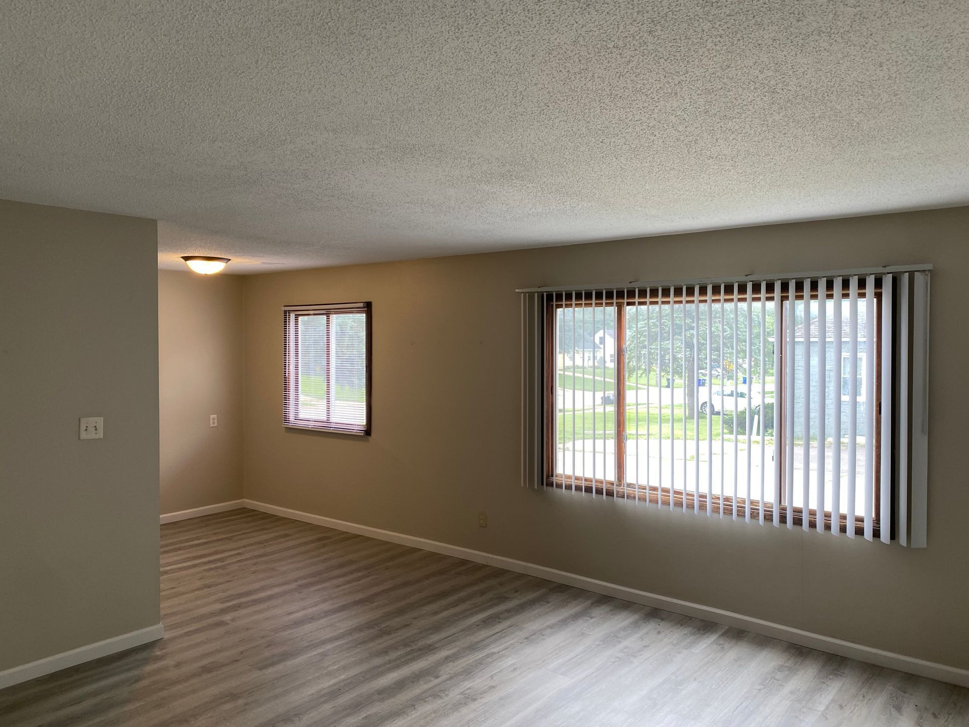 White two-story apartment building with gray shutters, landscaped front beds, and a gravel driveway