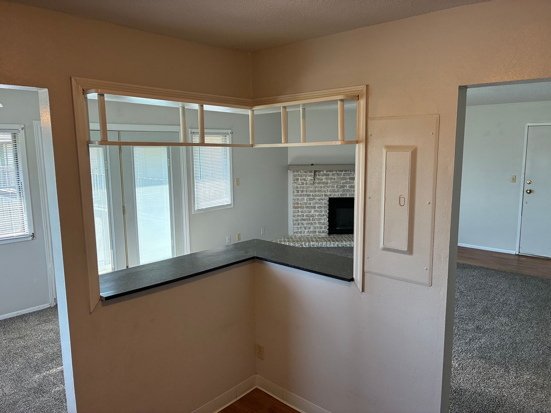 Small empty interior window opening with dark countertop and white trim in a beige room