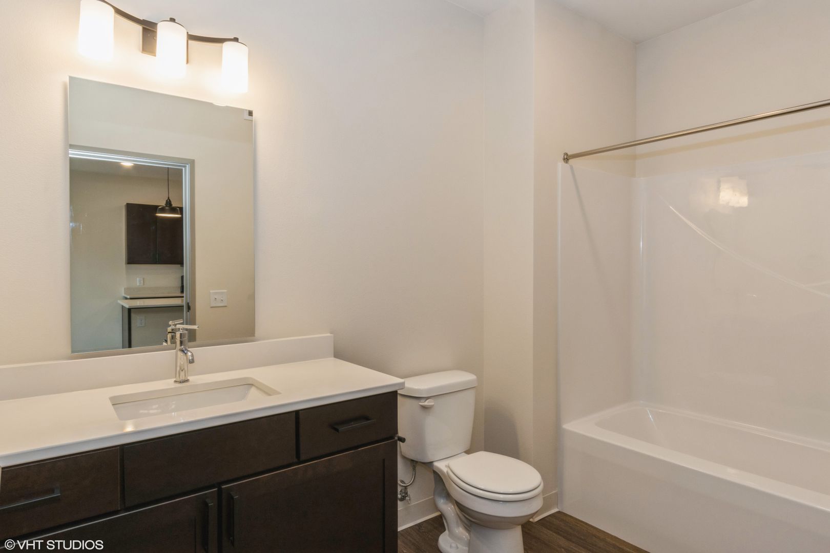 Small bathroom with bathtub, toilet, sink vanity, and gray walls and floor.