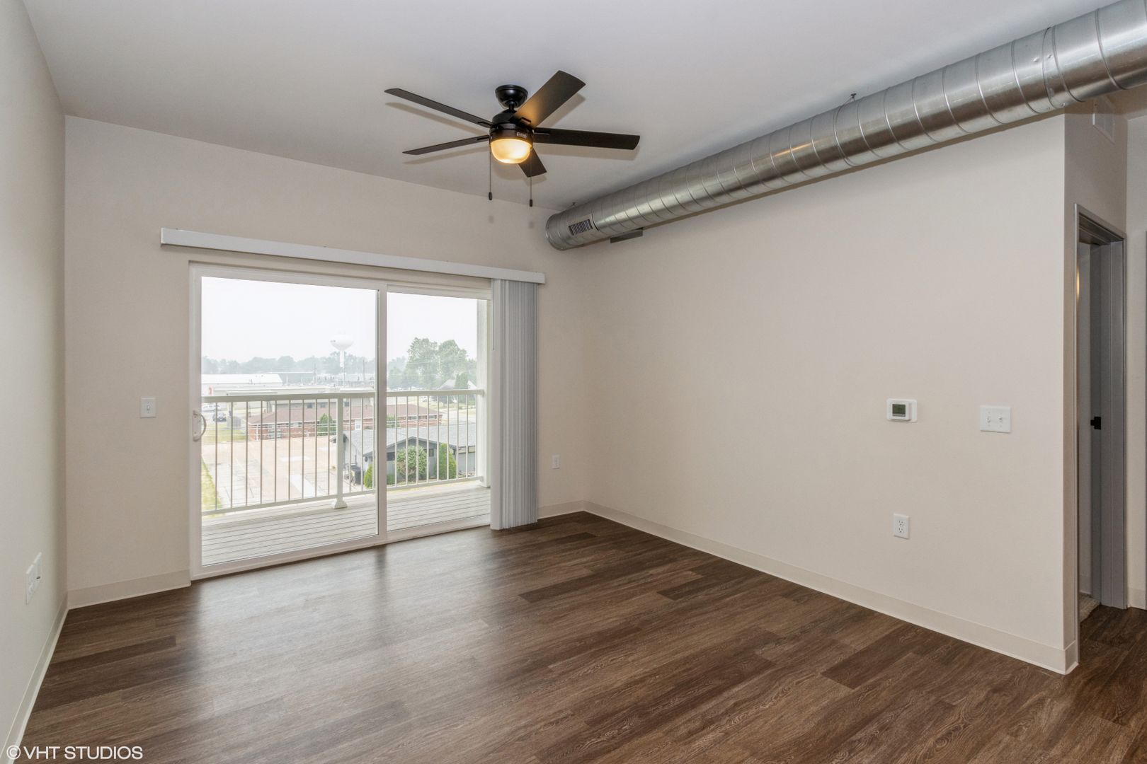 Empty gray room with wood-look floors, white doors, and a ceiling light.