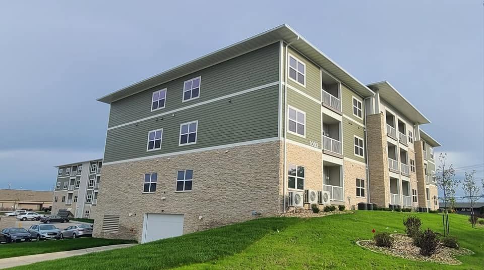 Apartment building with a steep triangular entrance, brown siding, and a central walkway