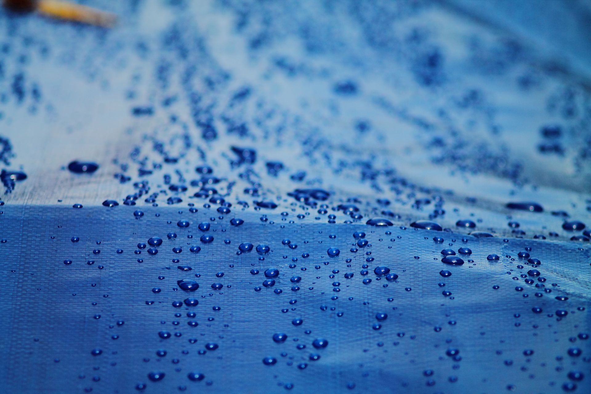 Bright blue canvas with water drops showcasing a waterproof surface. Bright blue canvas with water drops showcasing a waterproof surface.