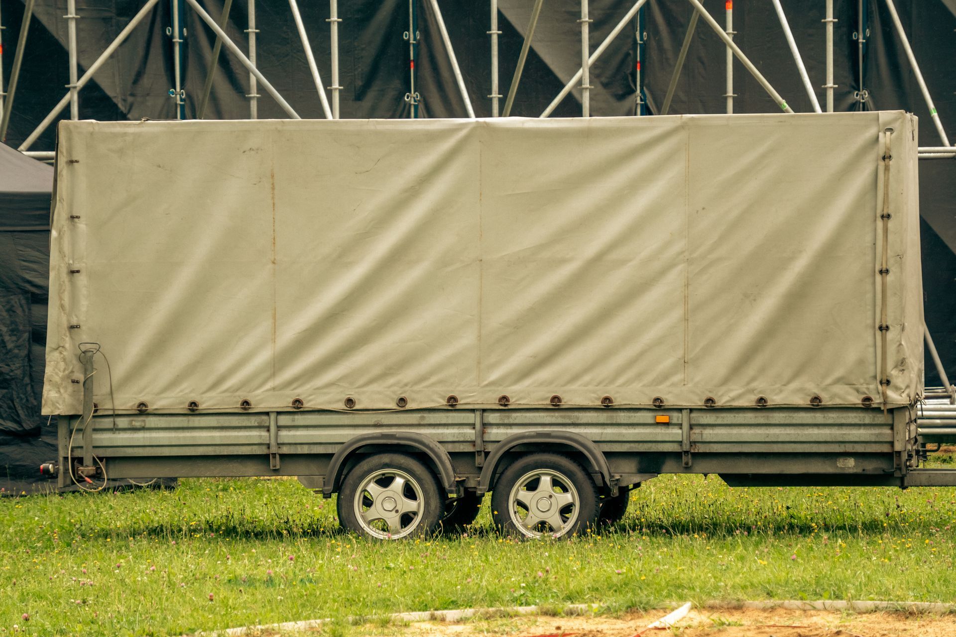 Industrial tarp systems covering a cargo trailer with a beige canvas tarp near scaffolding