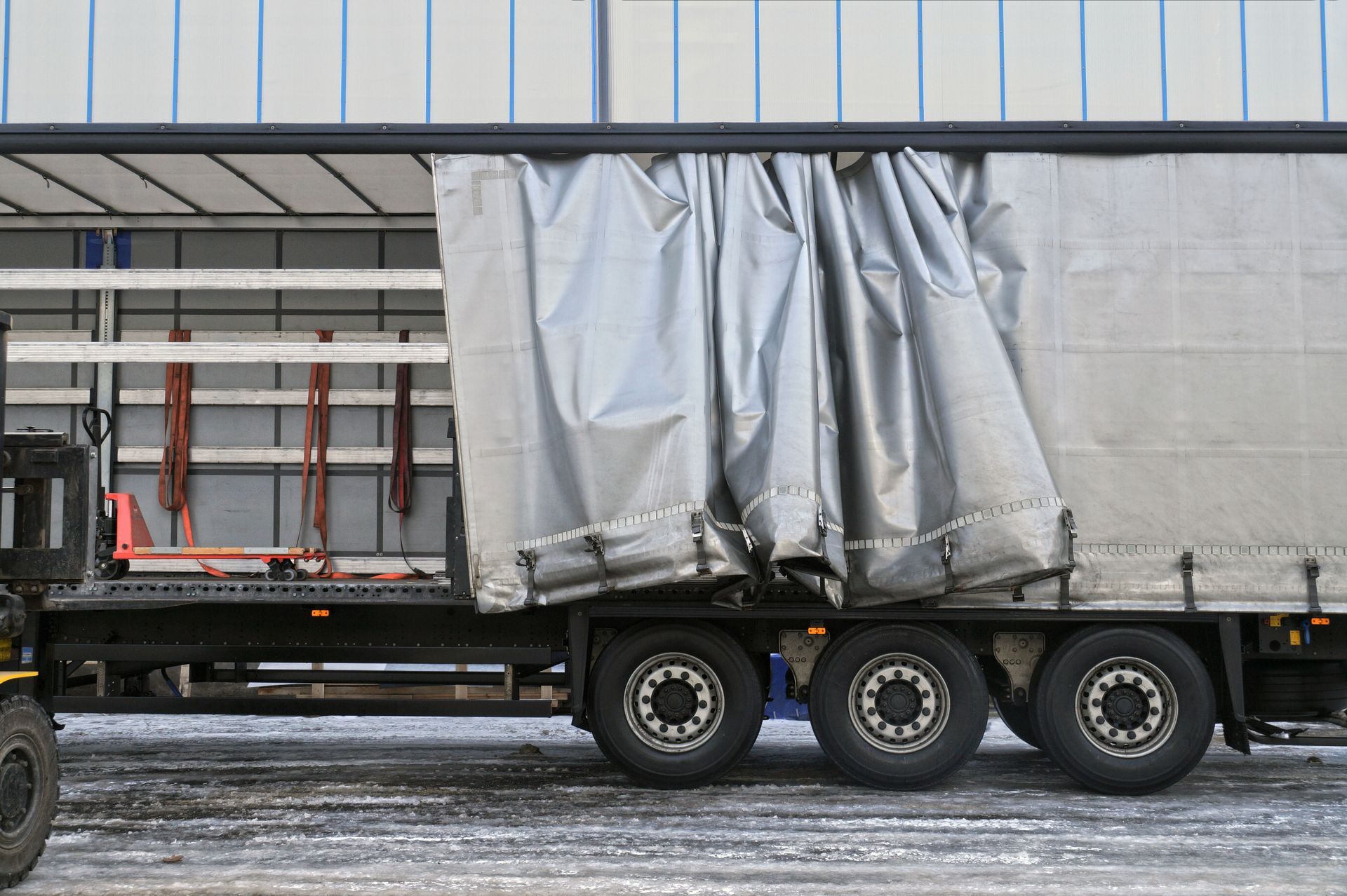 Side view of a truck with its tarp pulled open, revealing the empty cargo area. Side view of a truck with its tarp pulled open, revealing the empty cargo area.
