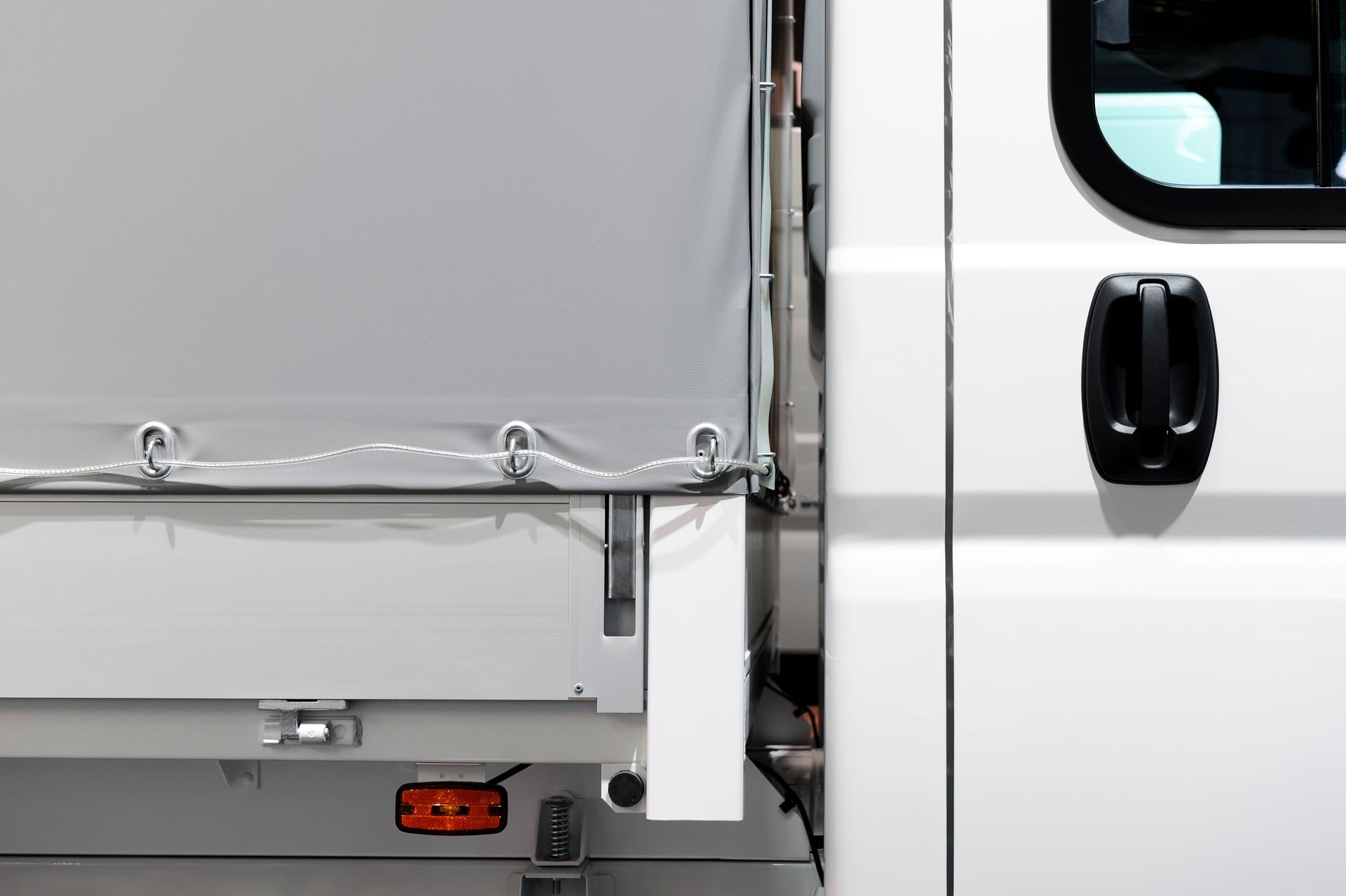 Commercial truck detail showcasing industrial tarp systems with white cab and gray cargo tarp.