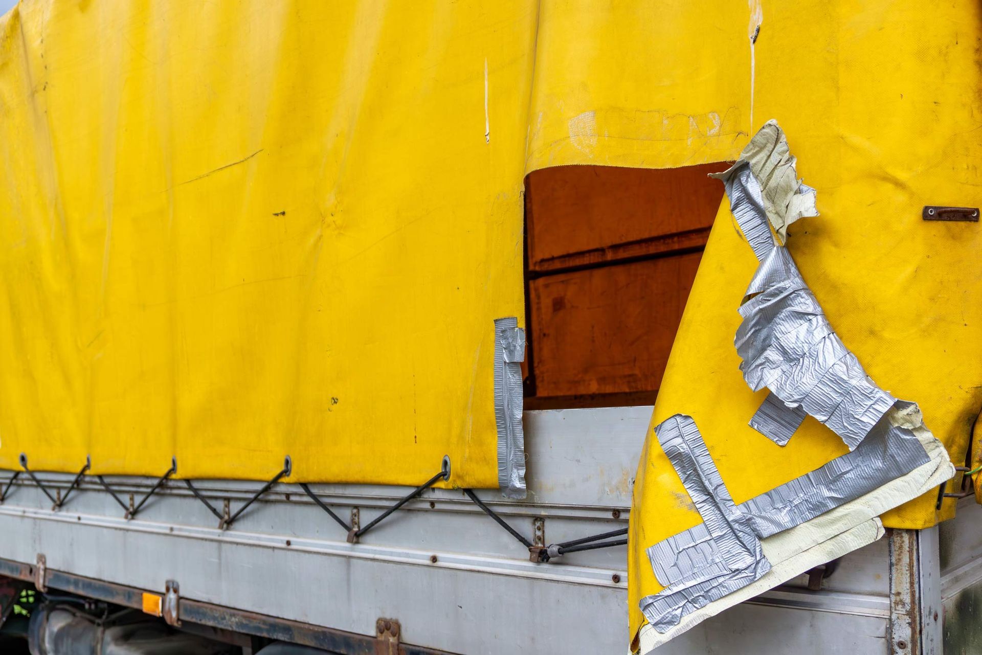 Industrial tarp cover system with yellow heavy-duty fabric on a transport trailer.