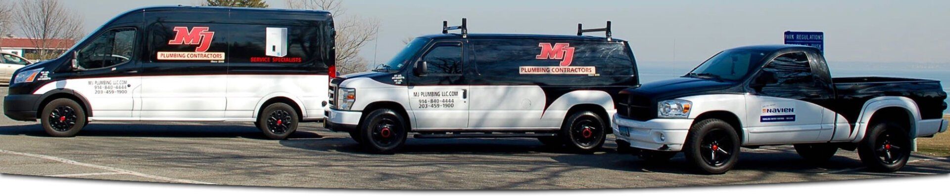 Three white-and-blue vans with red logos parked in a row on a dirt lot