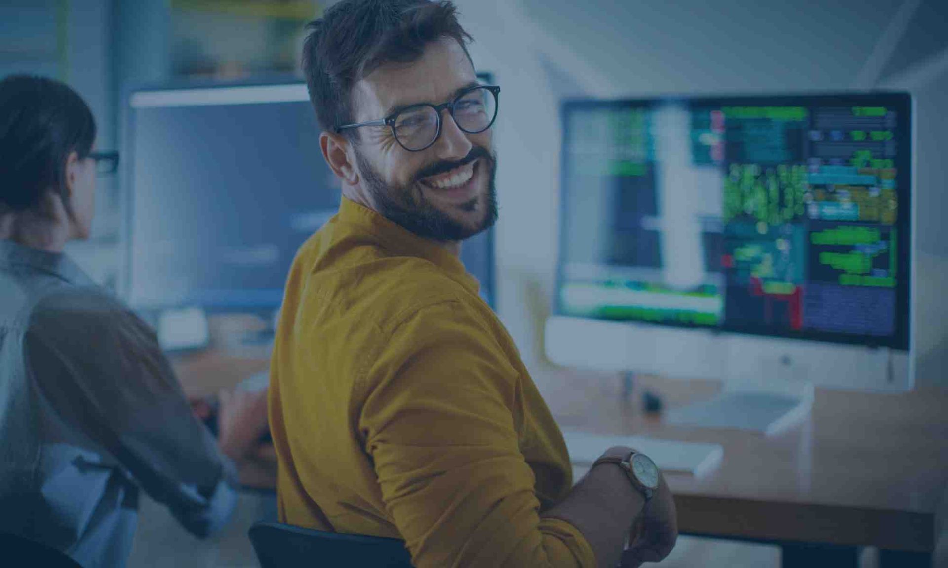 A man is smiling while sitting in front of a computer.