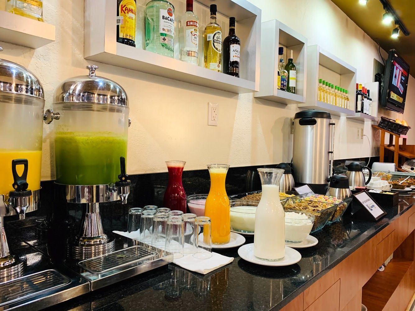 A buffet with a variety of drinks and food on a counter.