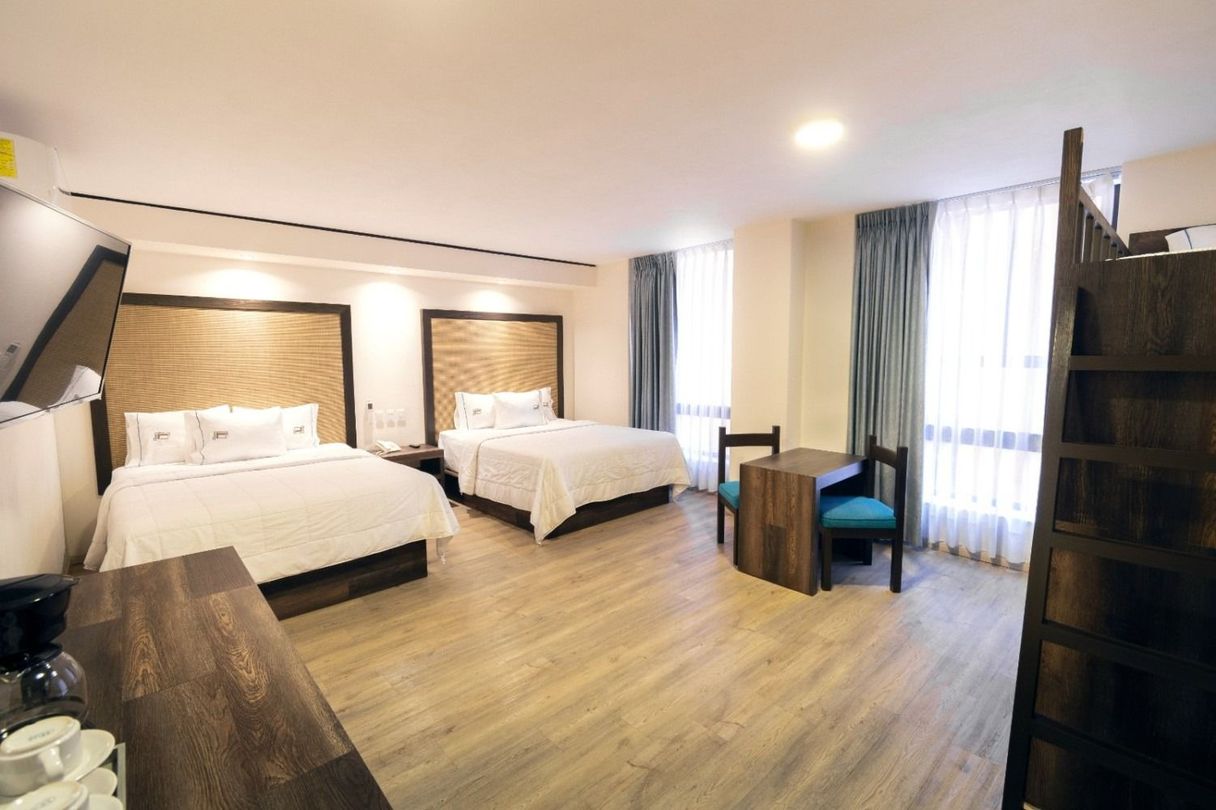 A hotel room with two beds , a table and chairs.