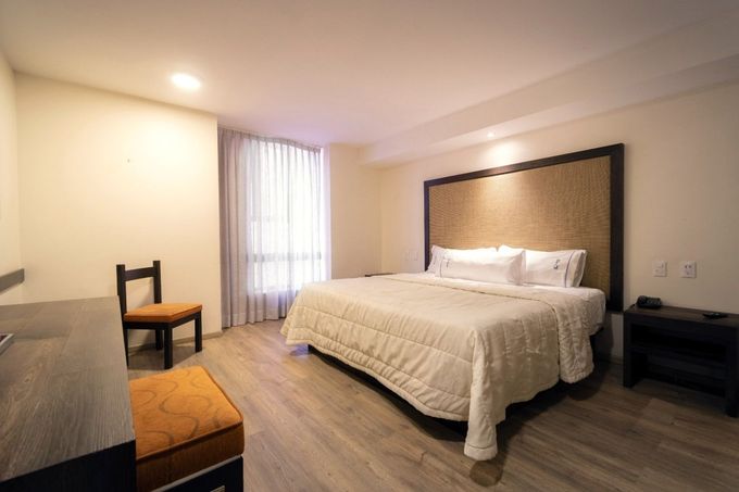 A hotel room with a king size bed and a chair.