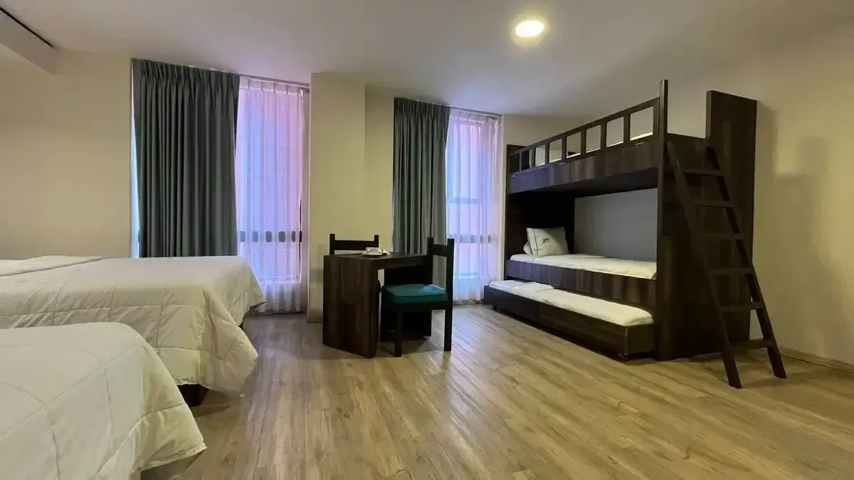 A hotel room with three beds and a bunk bed.