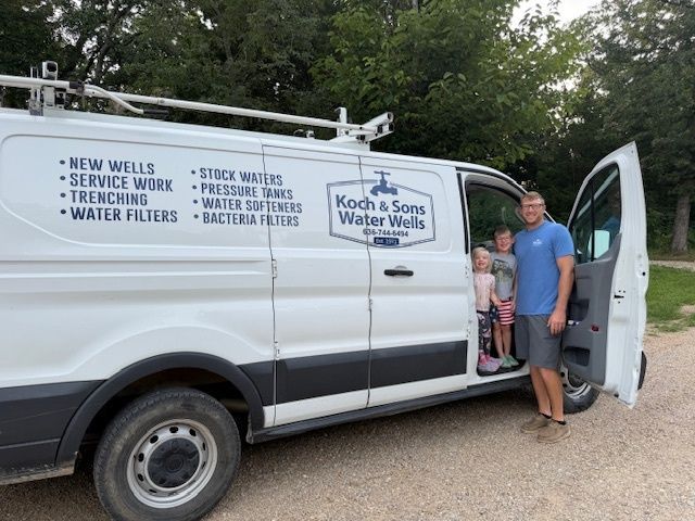 Water treatment van with company logo parked by trees; a man stands beside the open passenger door.