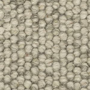 A close up of a wool rug with a knitted pattern.