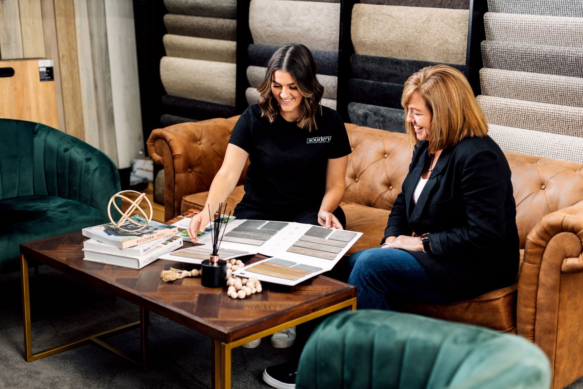Two women are sitting on a couch looking at a book.