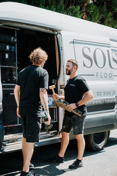 Two men are standing next to a white van.