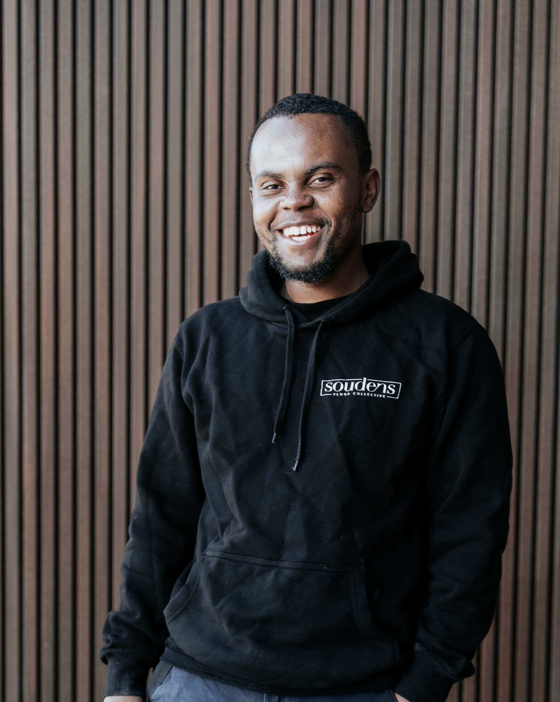 A man wearing a black shirt with the word sotheby 's on it is smiling.