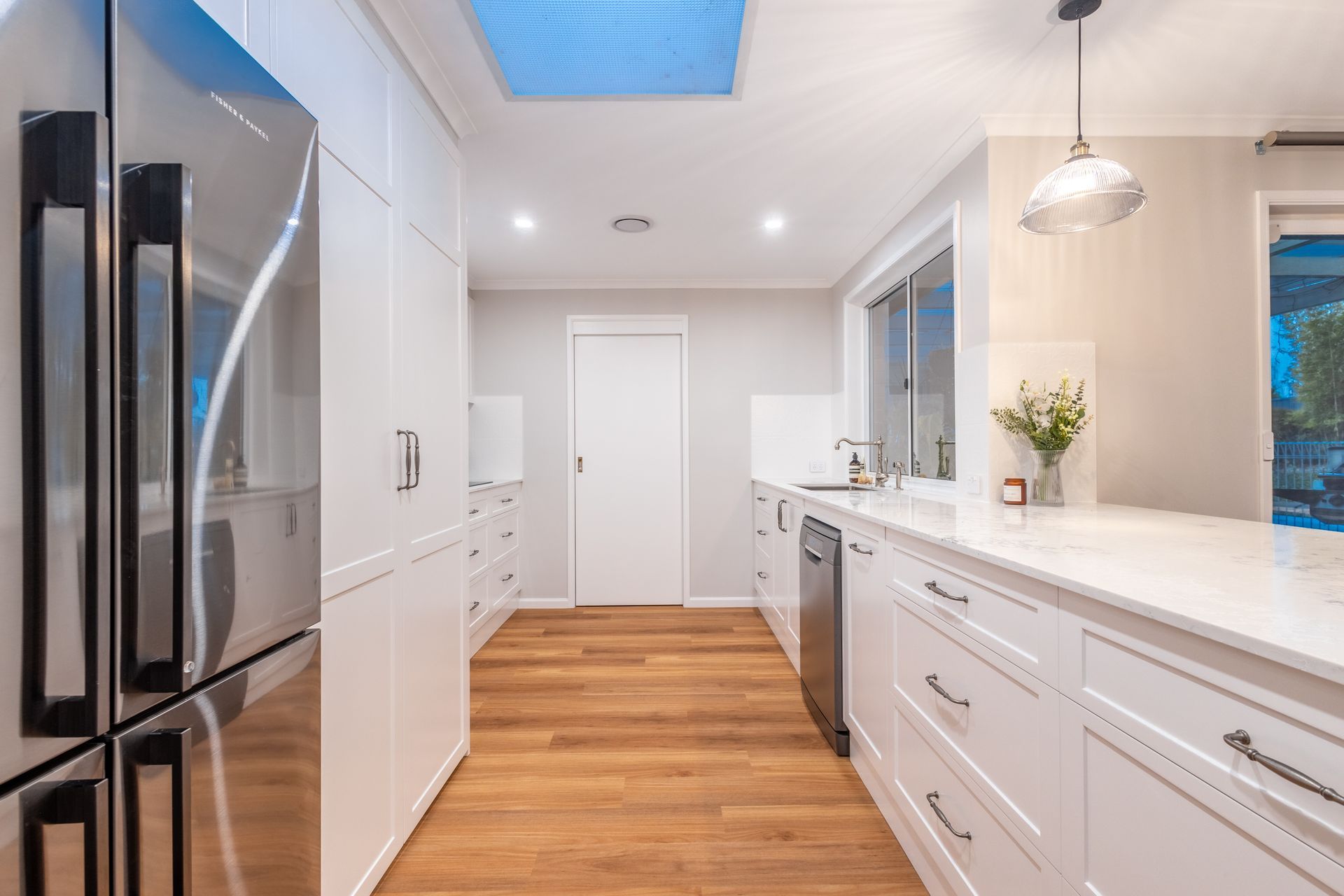 A kitchen with white cabinets , stainless steel appliances and a skylight.