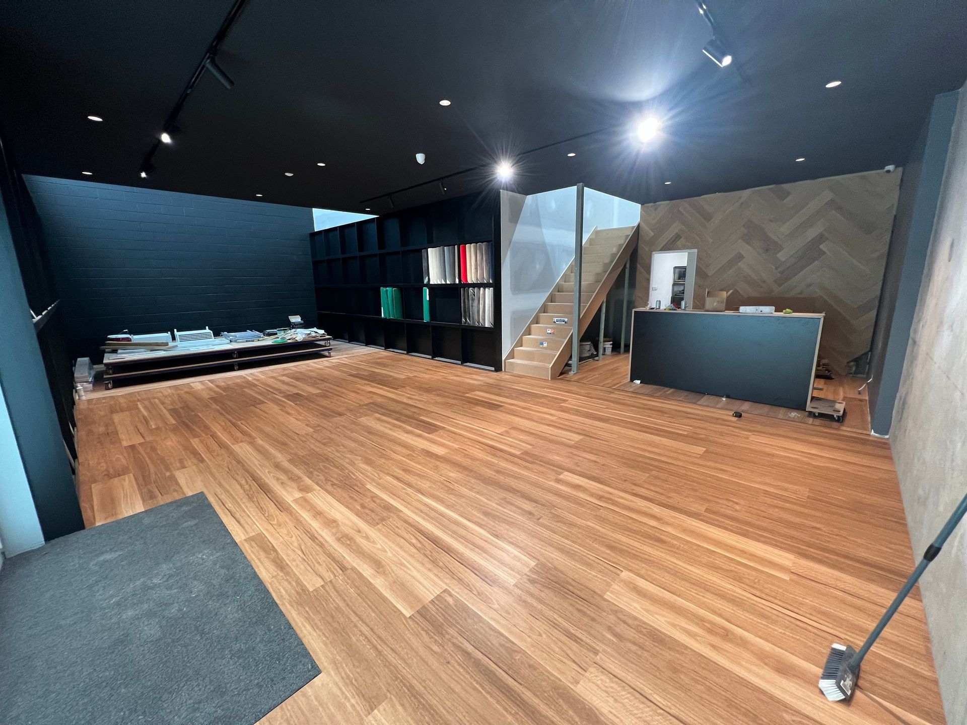 Modern loft interior with wood floor, black walls, staircase, and a kitchenette counter