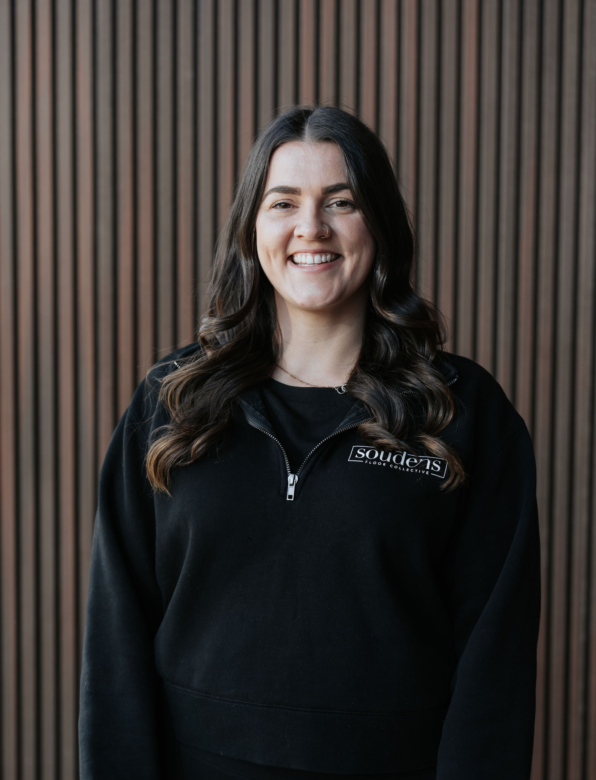 A woman is wearing a black t-shirt and smiling.
