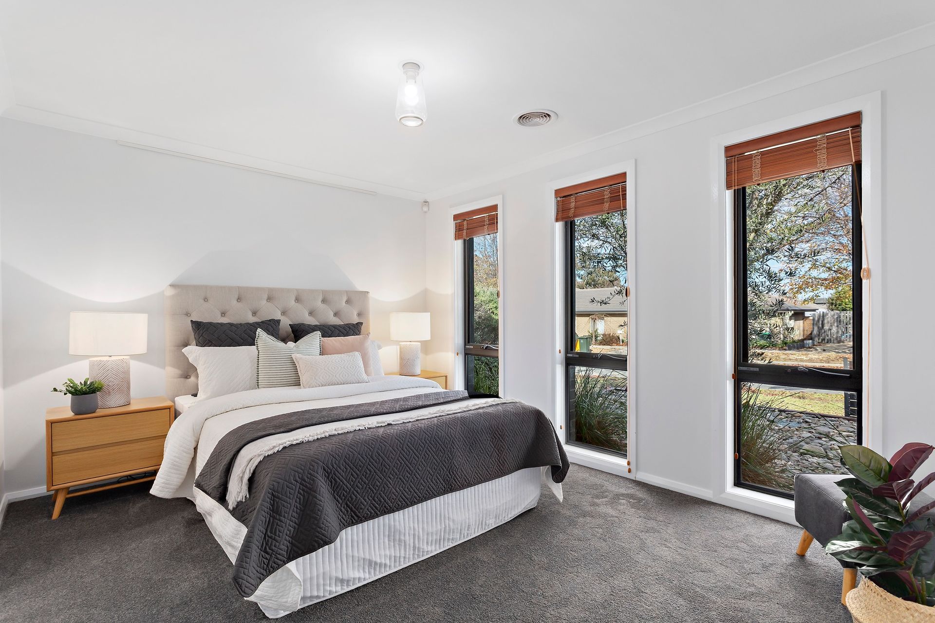A bedroom with a large bed , two windows and a chair.