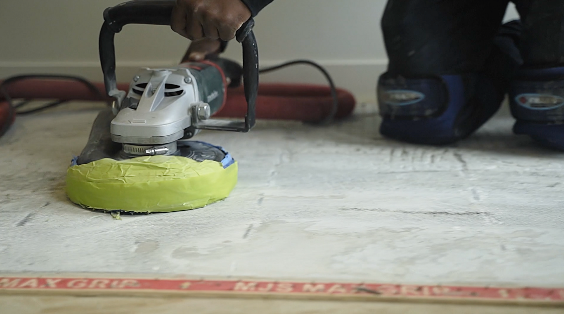 A person is using a grinder to polish a tile floor.