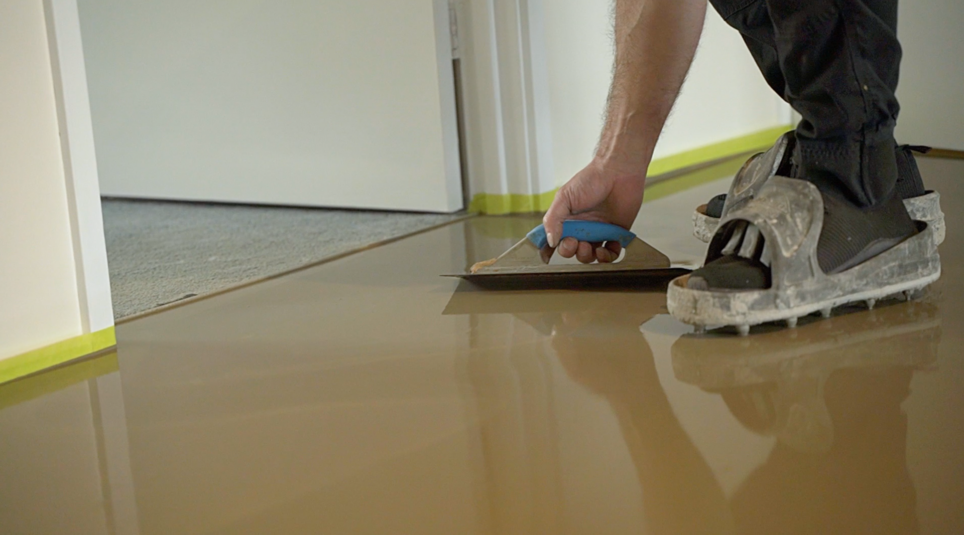 A person is spreading a concrete floor with a trowel.