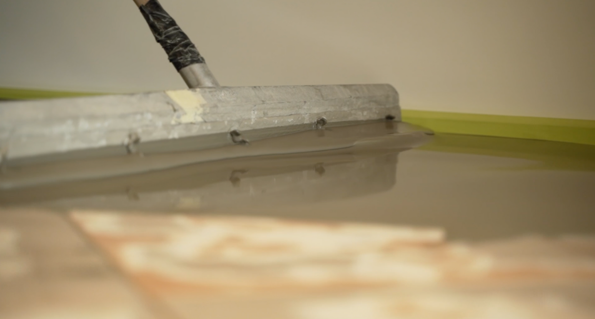 A person is spreading concrete on the floor with a trowel.