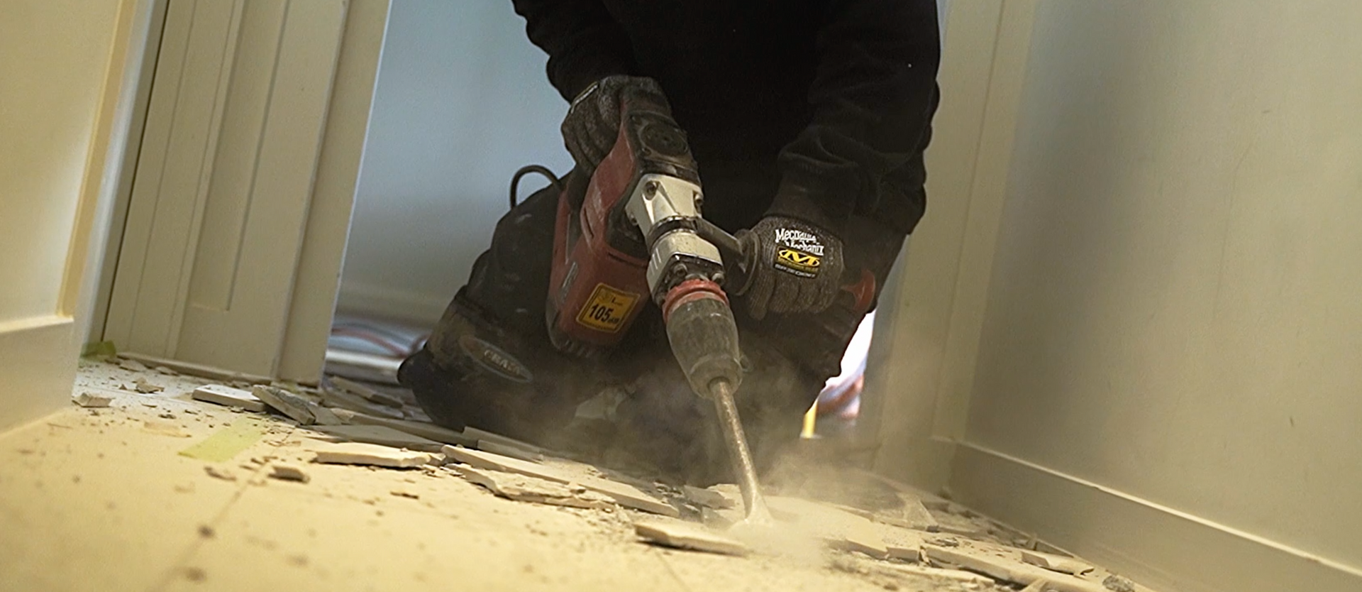 A man is using a hammer to drill a hole in the floor.
