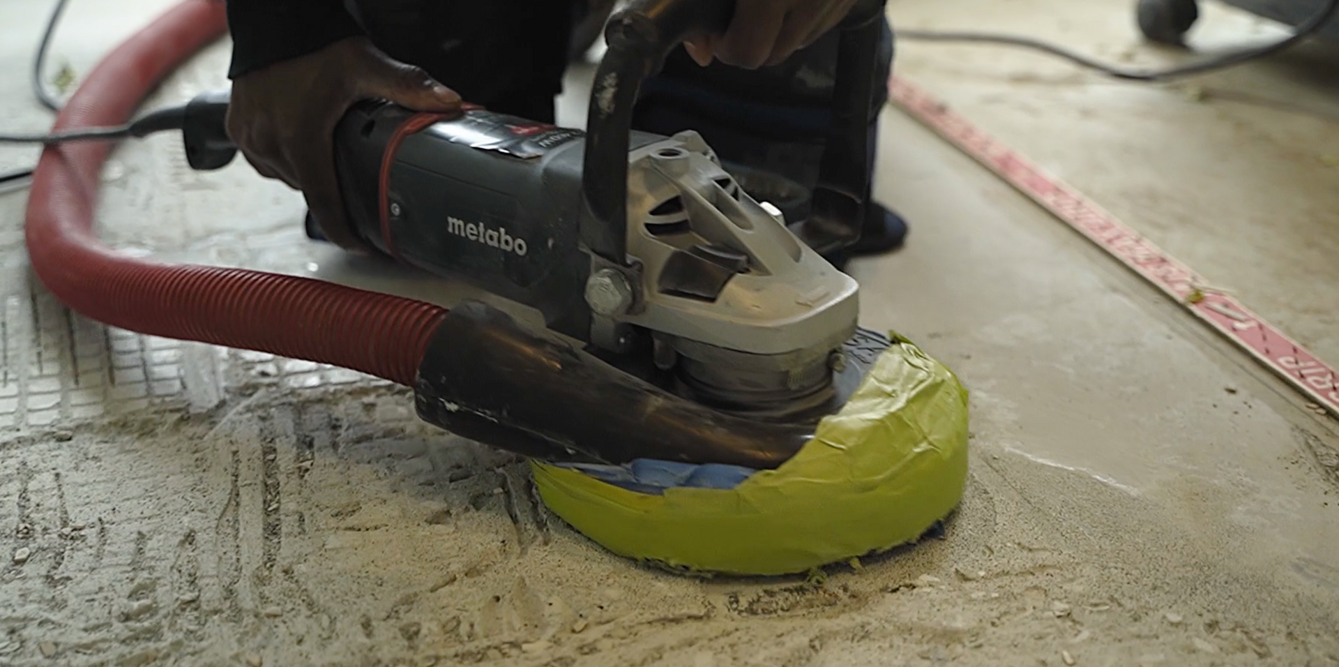 A person is using a grinder on a concrete floor.