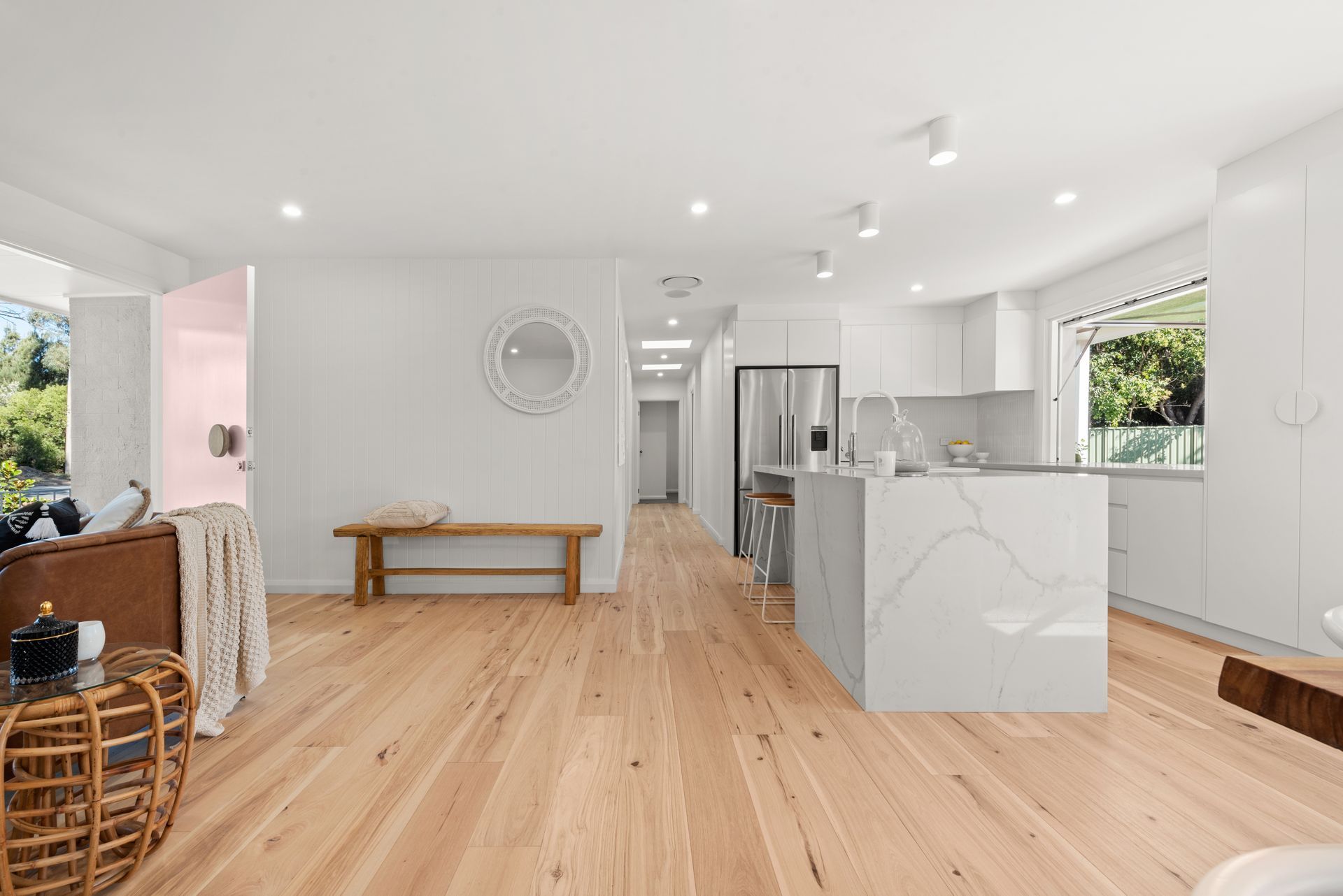 A living room with hardwood floors and a kitchen with white cabinets.
