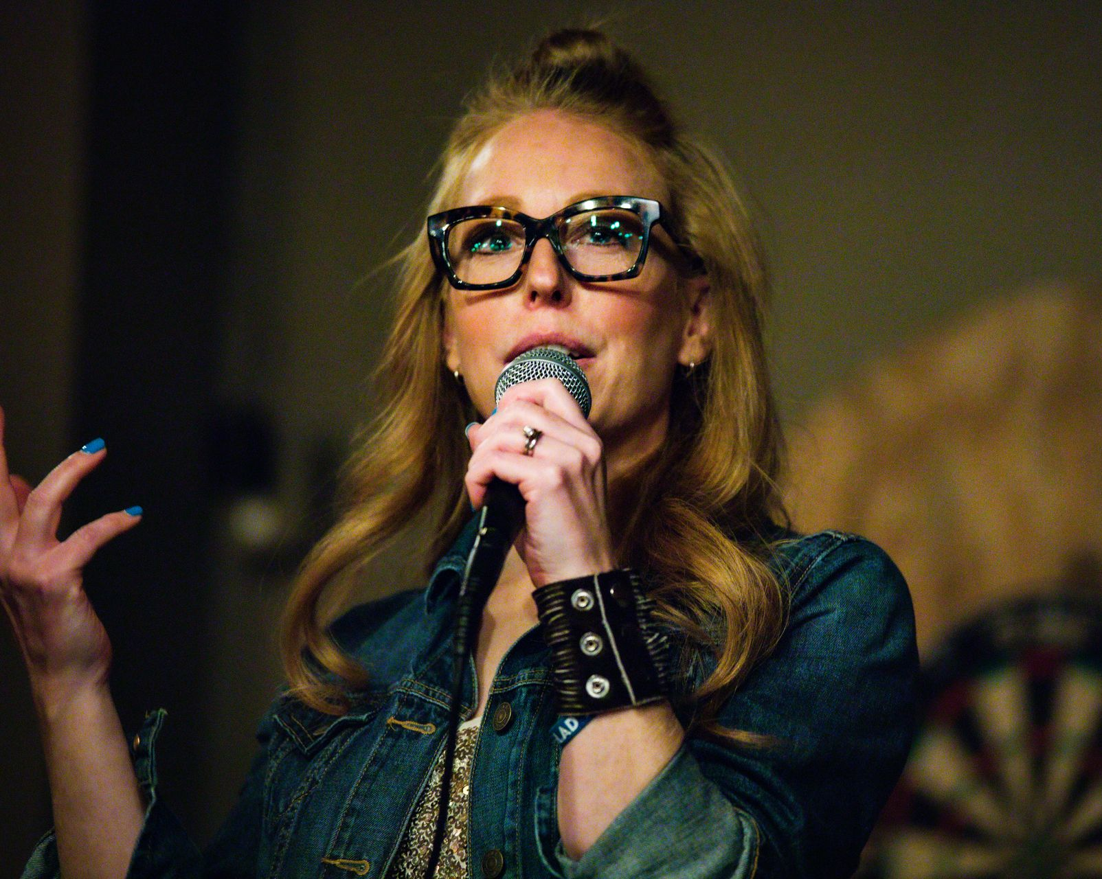 People laughing at an event, woman covers her mouth, others smile in a line indoors.