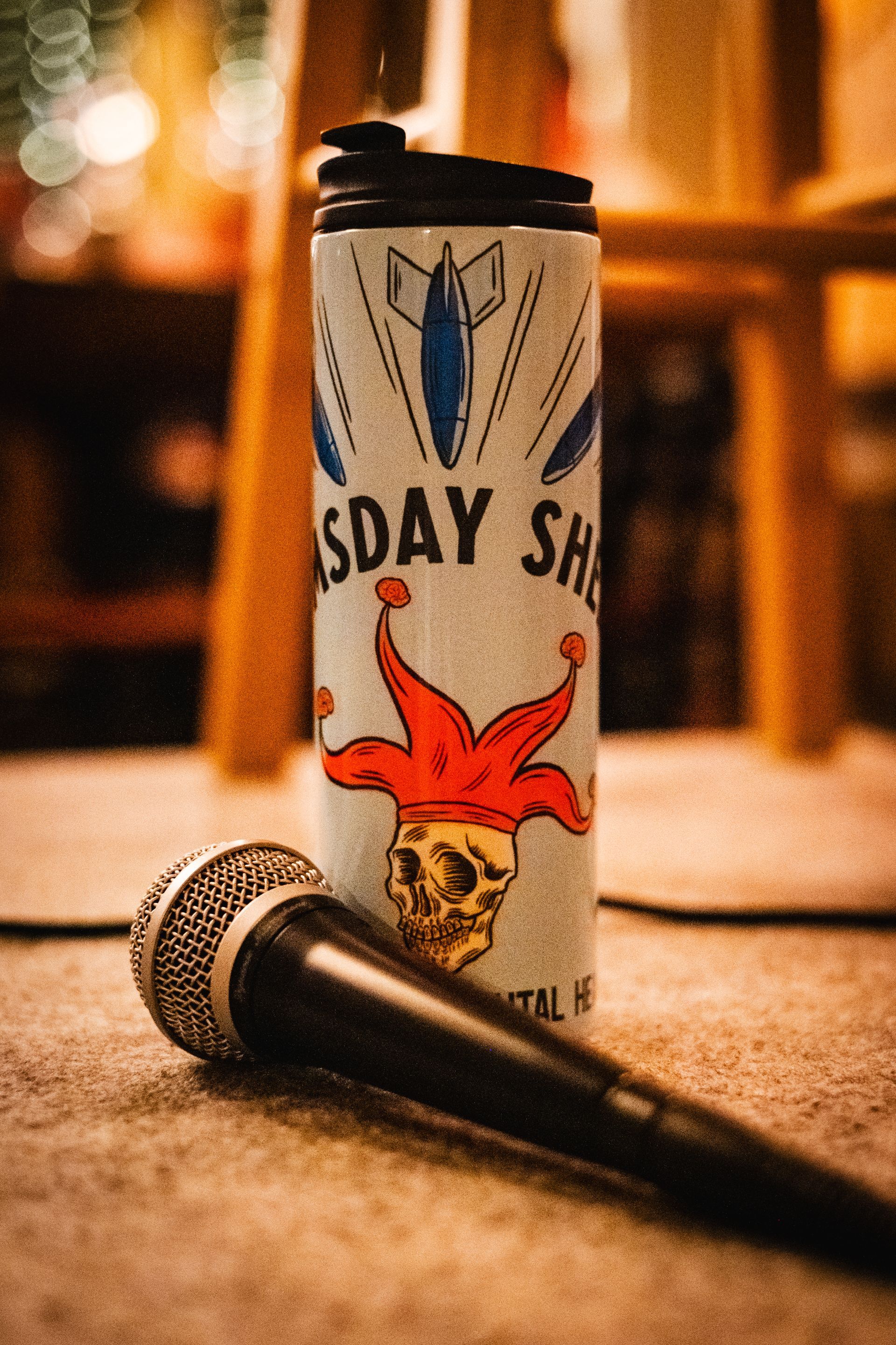 Microphone beside a metal tumbler with a skull wearing a jester's hat;