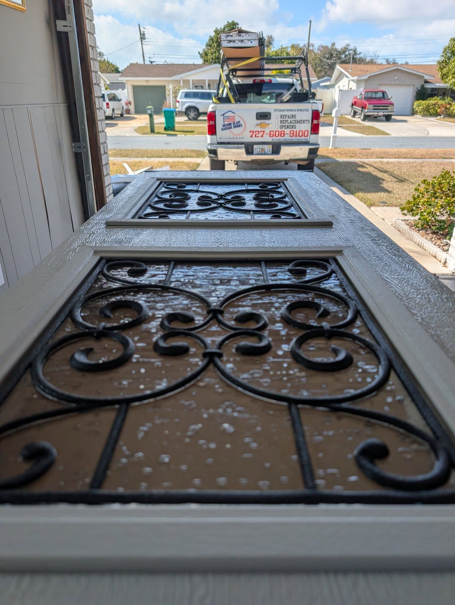 Two decorative doors with black ironwork, sitting in front of a white truck.