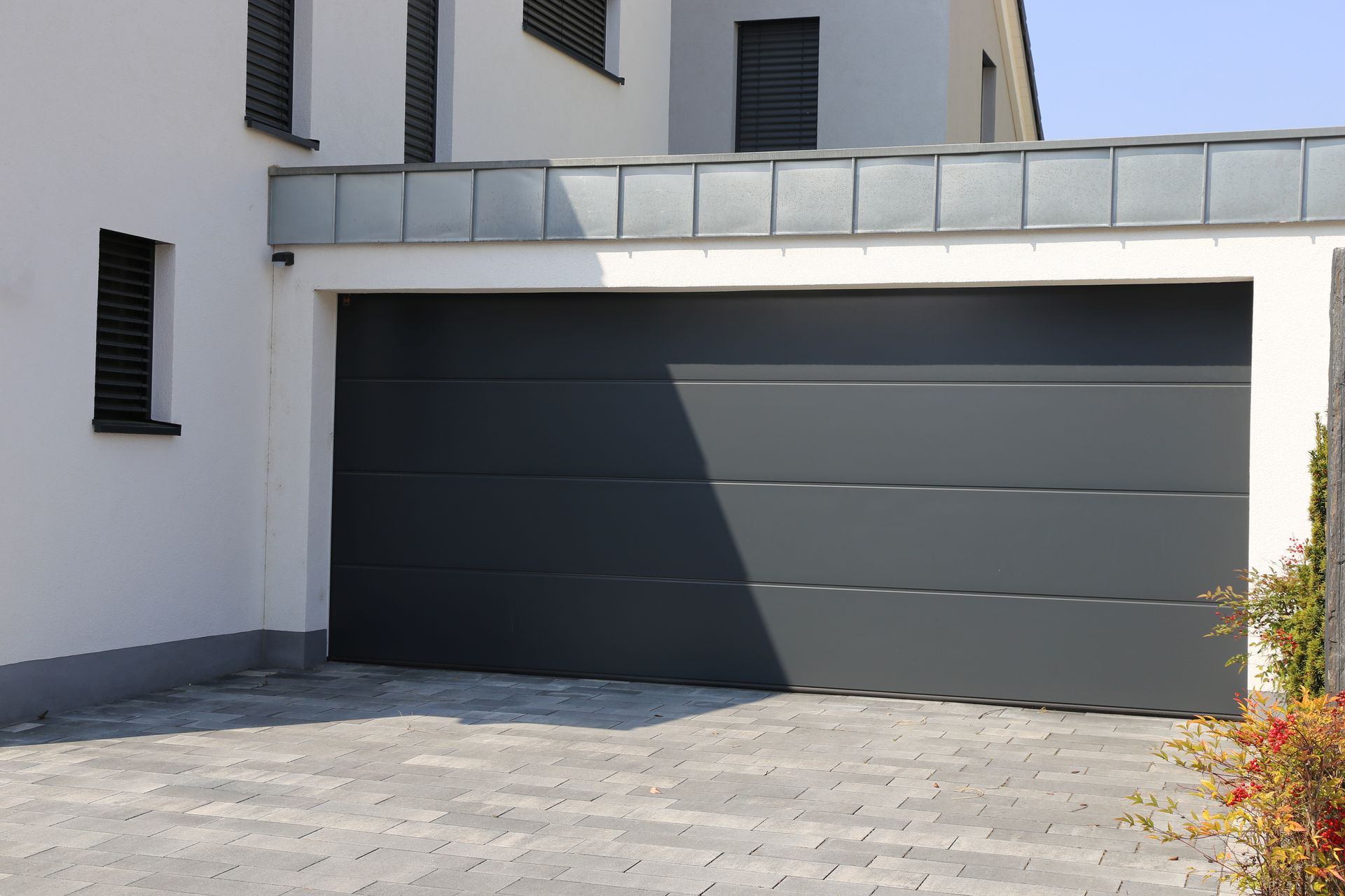Gray garage door on a white building, brick driveway. Gray garage door on a white building, brick driveway.