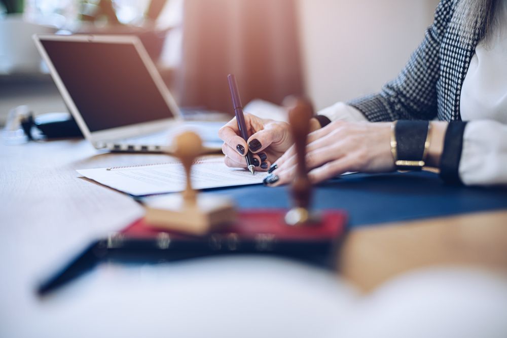 A woman is sitting at a desk writing on a piece of paper