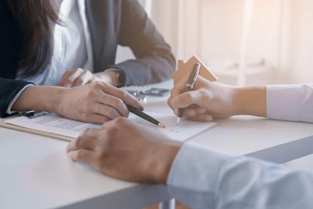 A man and a woman are sitting at a table writing on a piece of paper