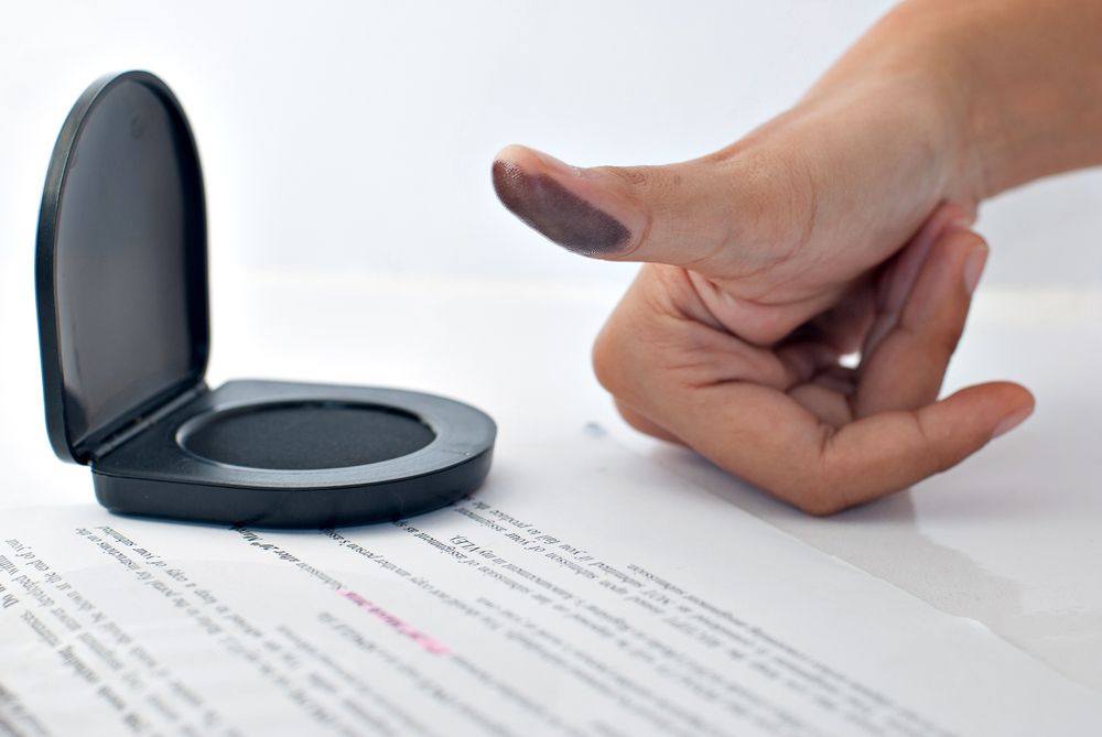 A person is putting their finger in a stamp on a piece of paper