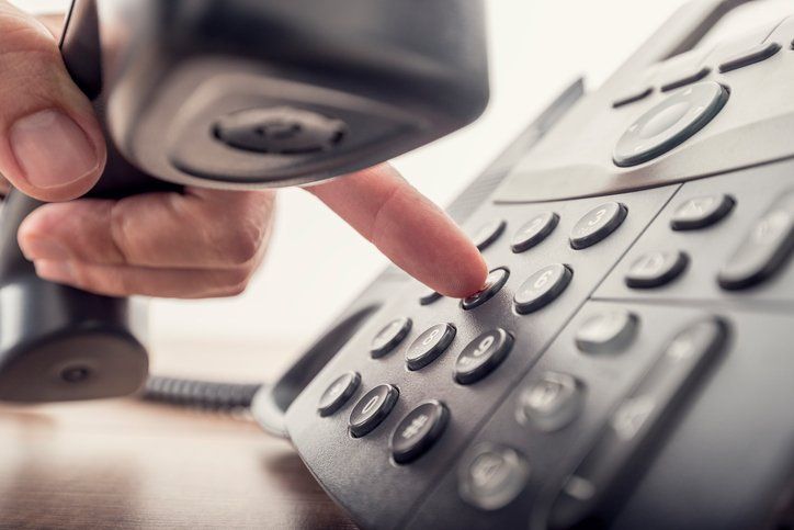 male hand holding telephone receiver while dialing