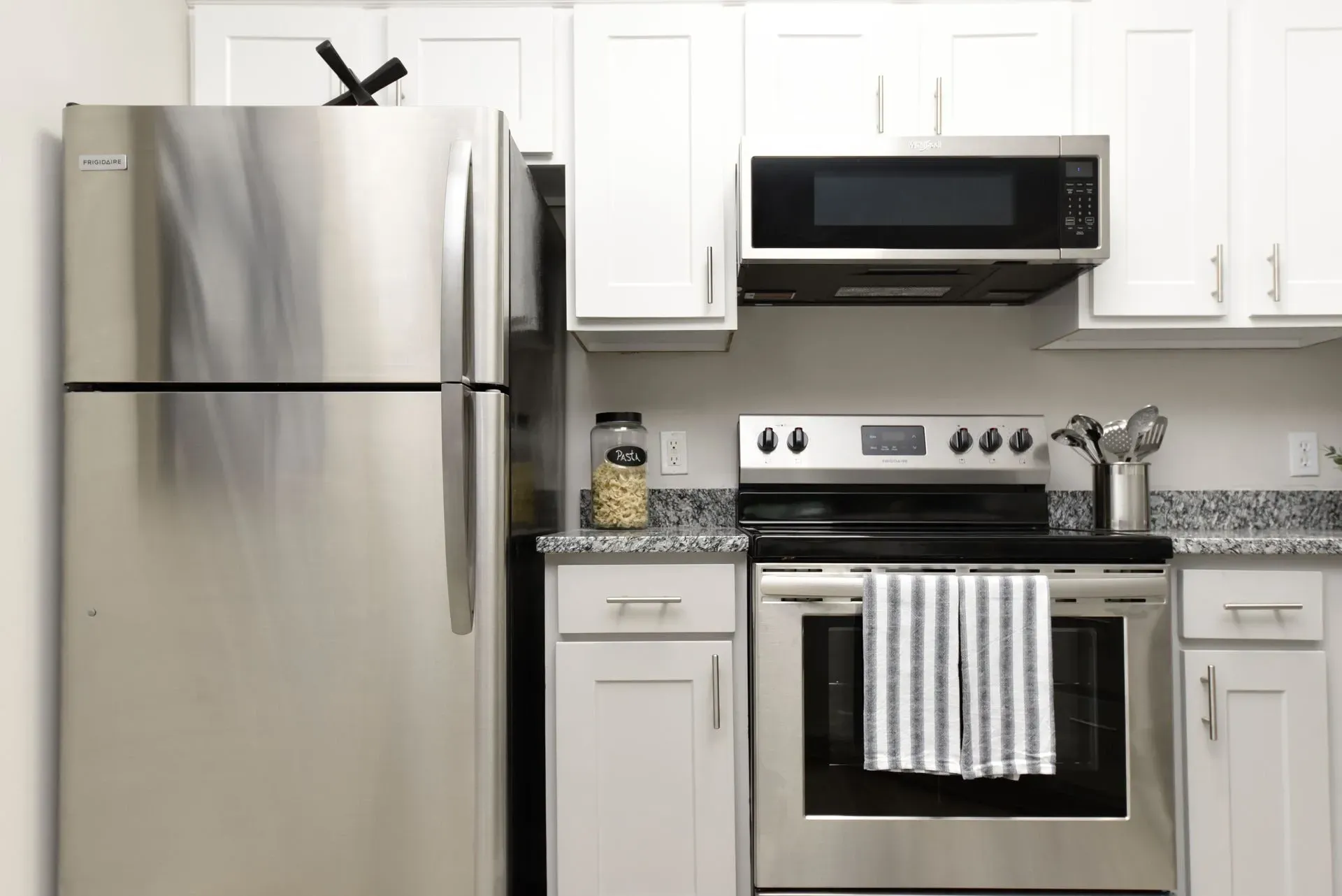 Modern kitchen with stainless steel appliances including a refrigerator, microwave, and oven.