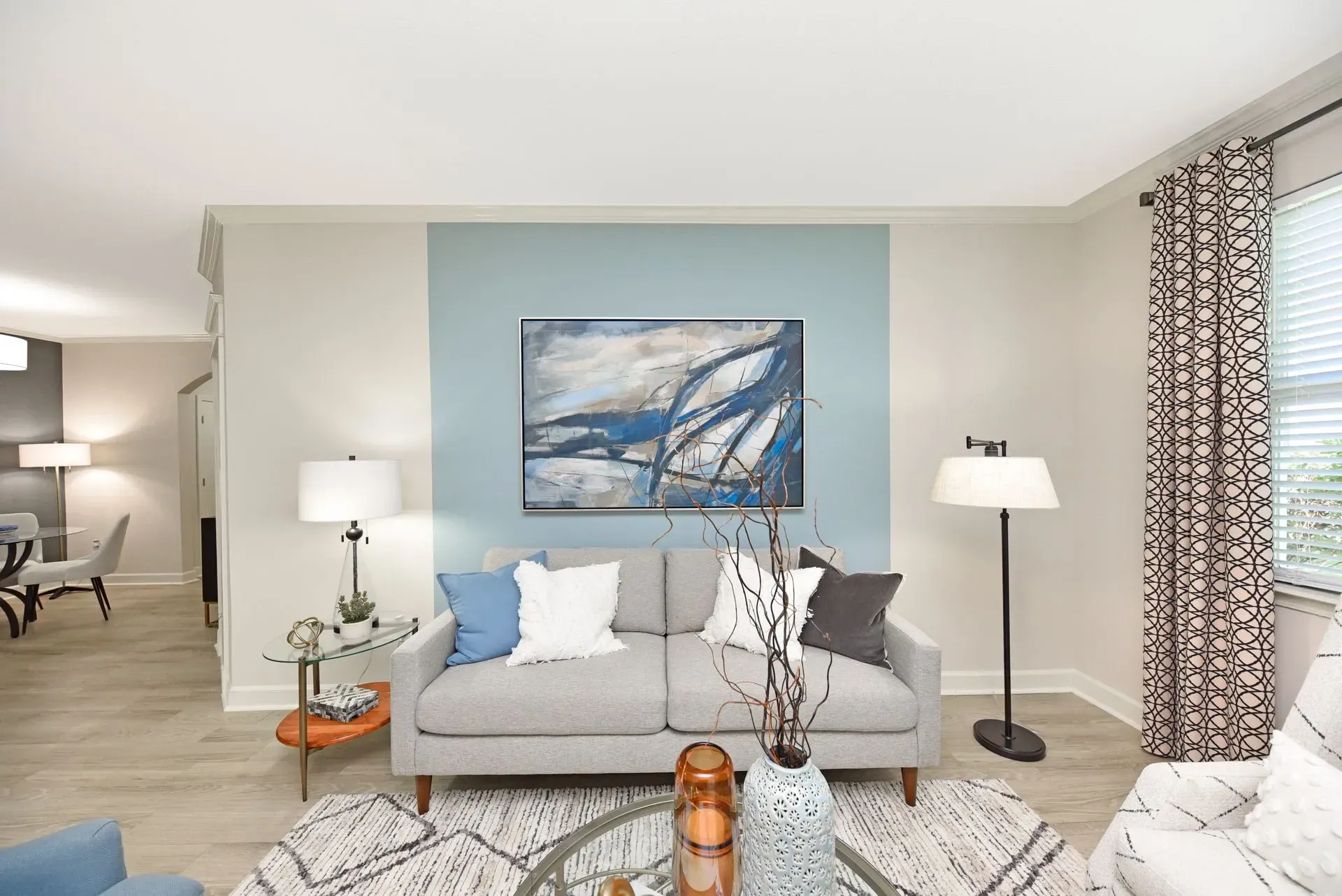 Modern living room with gray sofa, abstract art, and floor lamp.