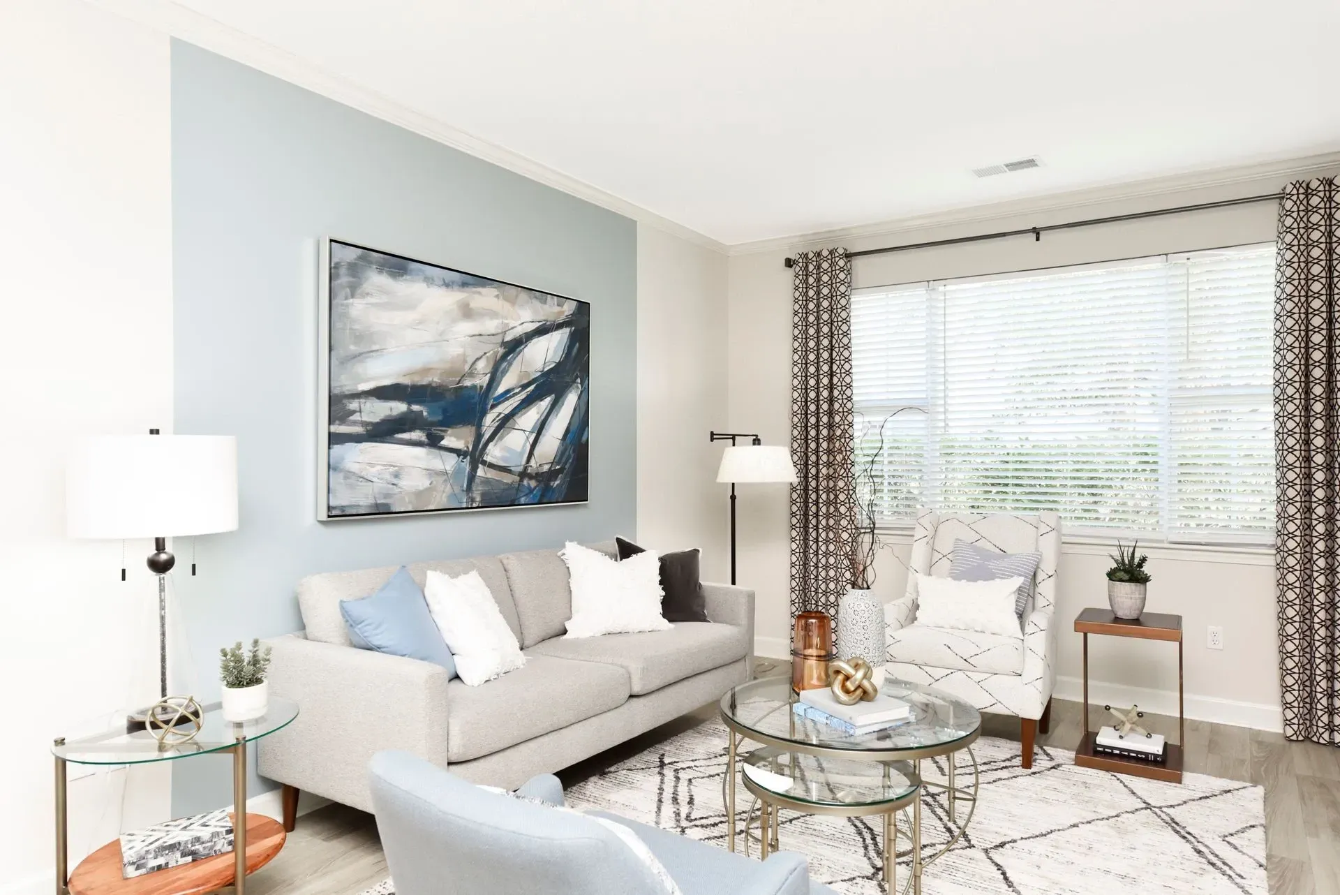 Modern living room with a gray sofa, accent chairs, coffee table, and abstract art.