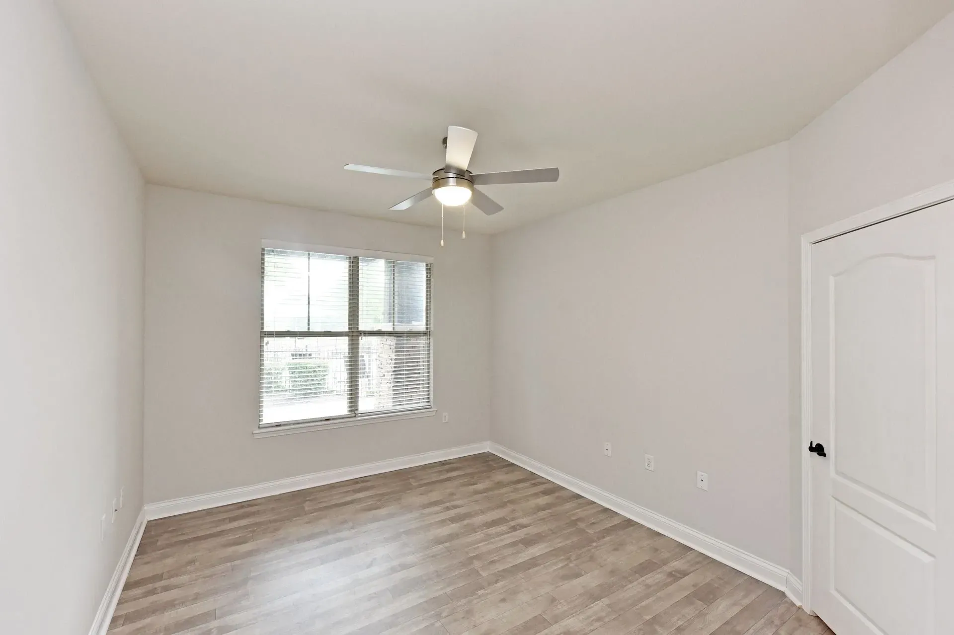 Empty bedroom with a ceiling fan and a window.
