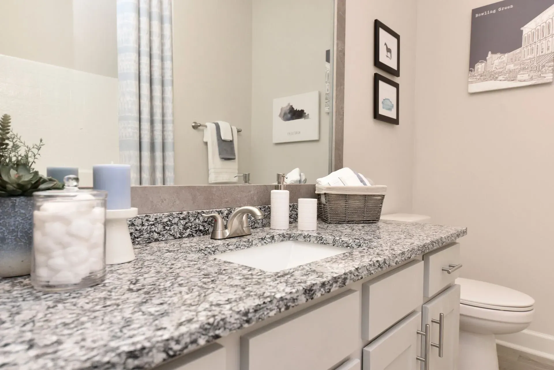 Modern apartment bathroom vanity with granite countertop, sink, and toilet.