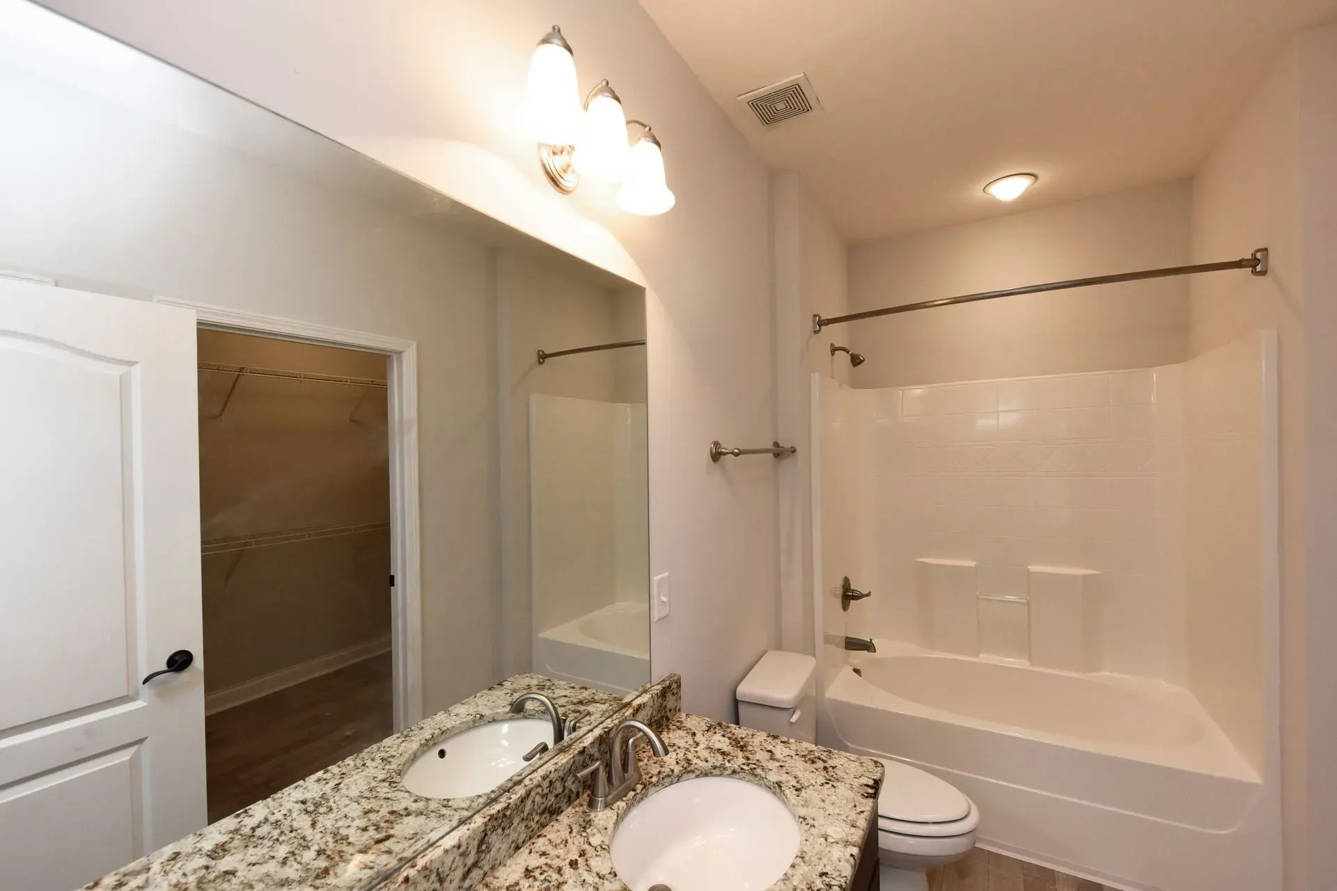 Bathroom with double vanity, toilet, and bathtub with shower