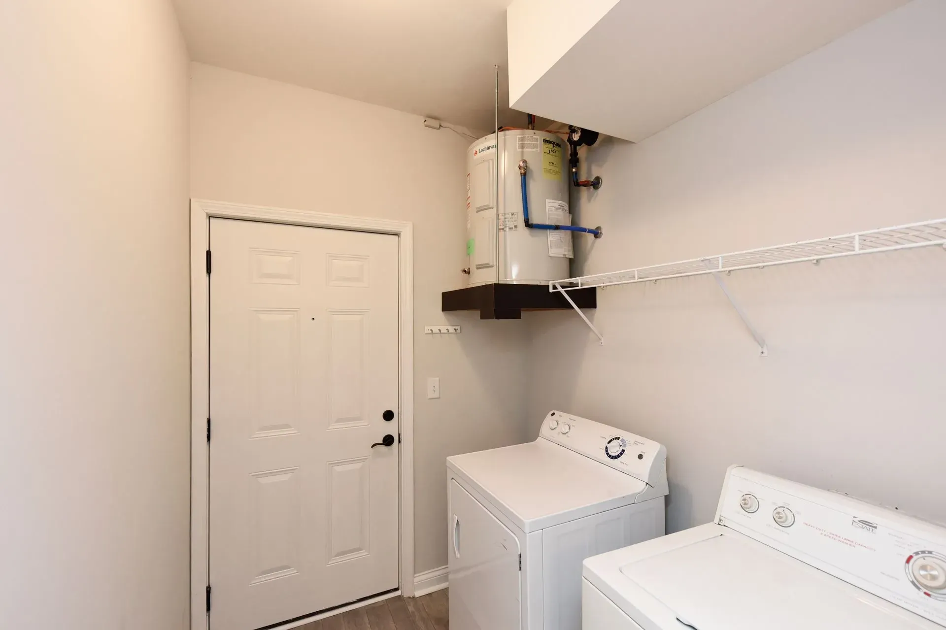Laundry room with washer and dryer, water heater, and shelving.