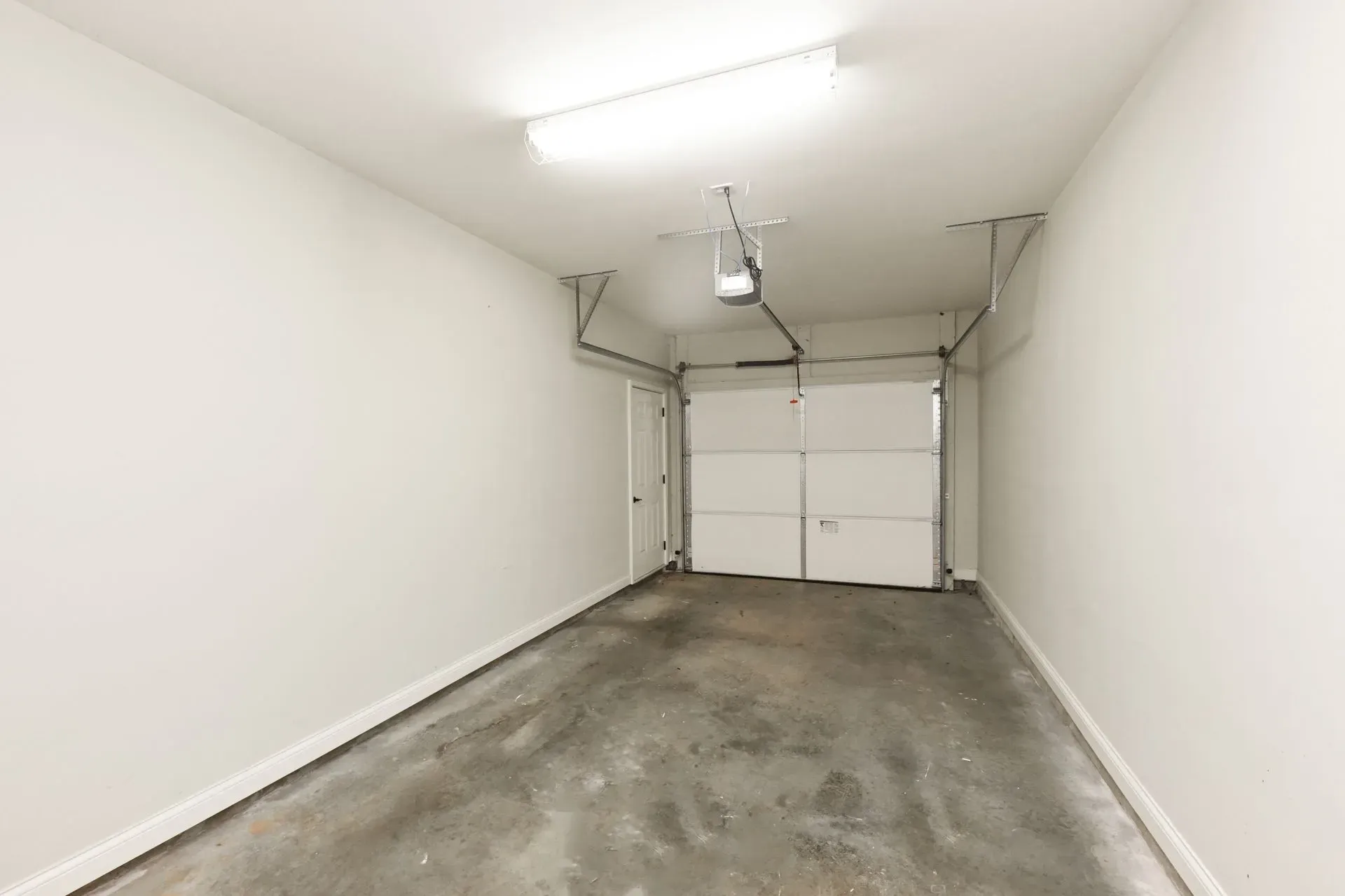 Interior of an empty garage with a white door and garage door.