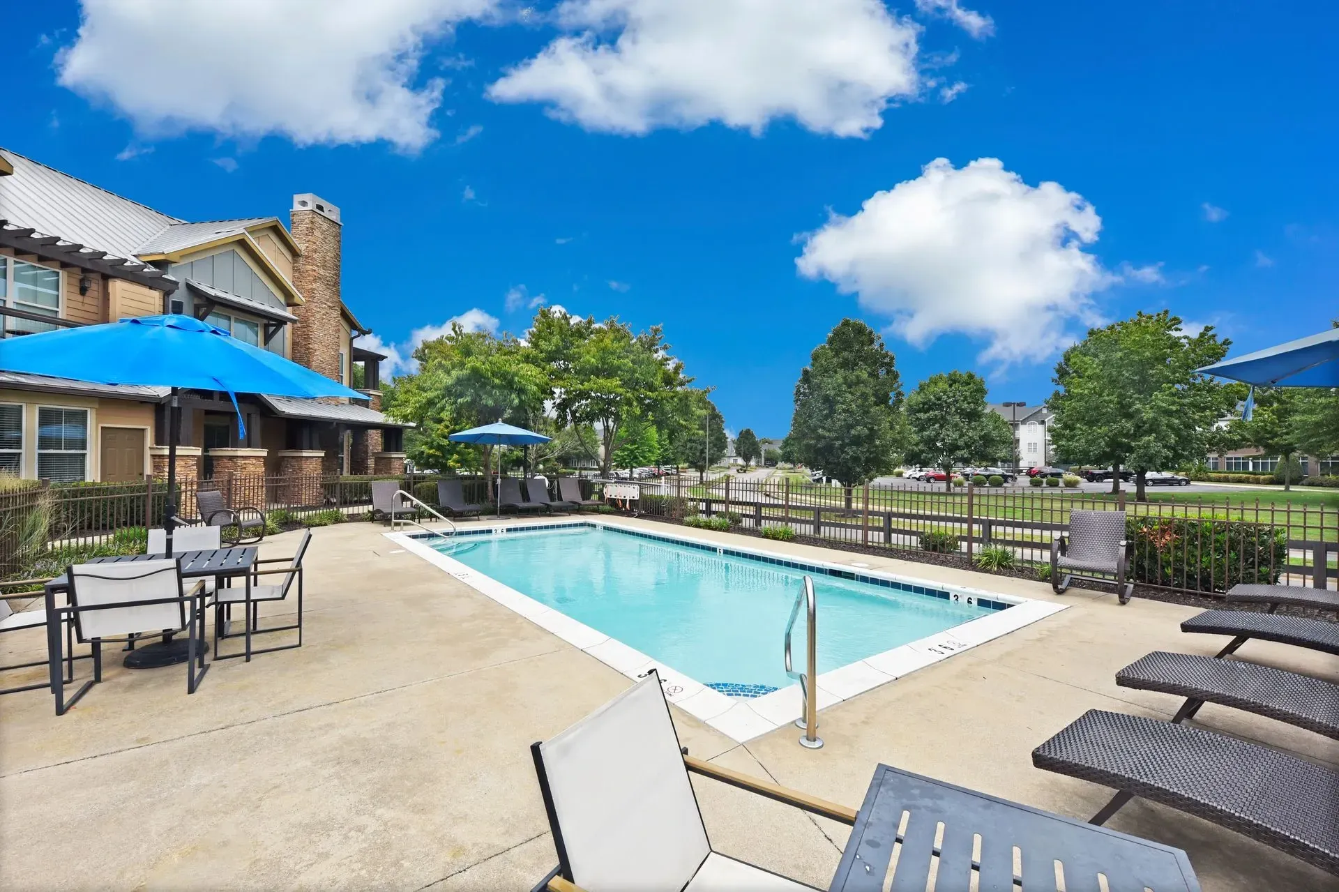 Outdoor swimming pool area with lounge chairs and tables.