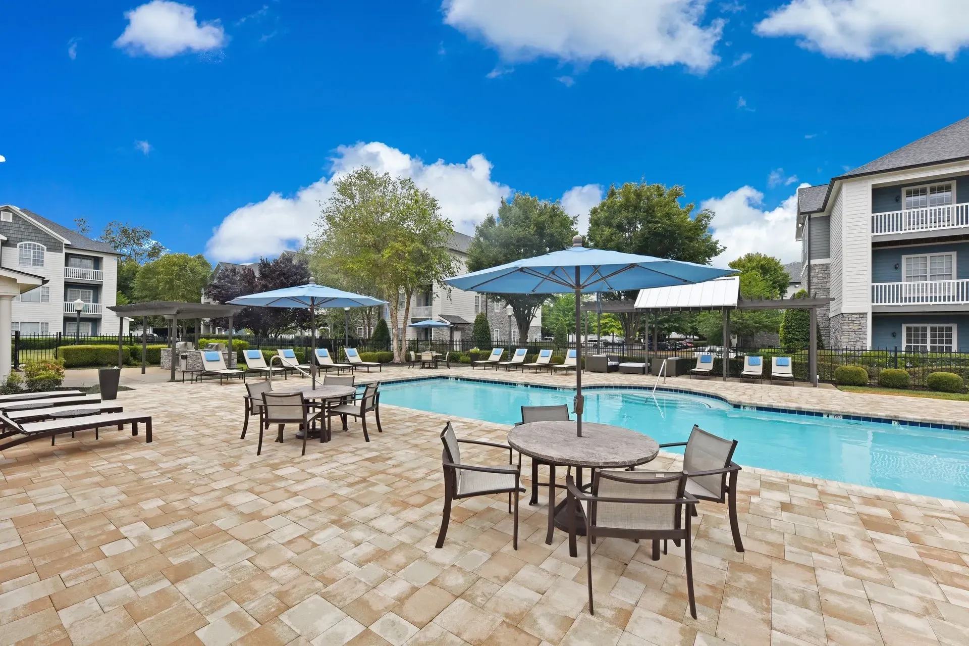 Resort-style pool with lounge chairs and outdoor seating under umbrellas.