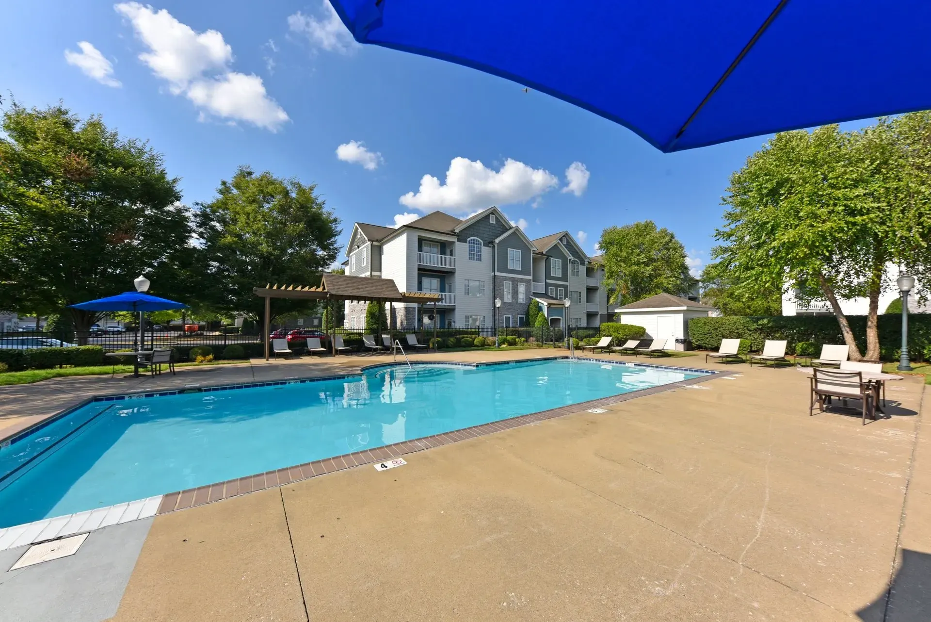 Swimming pool and apartment building exterior on a sunny day.